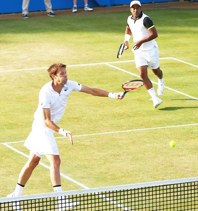 Canada's Daniel Nestor of Canada smashes as his partner Leander Paes