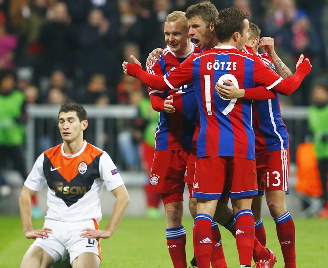 Shakhtar Donetsk's Taras Stepanenko, left, reacts as Bayern Munich's Thomas Mueller, third left, celebrates 