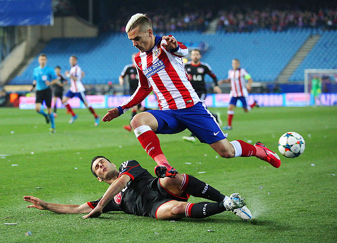 Antoine Griezmann of Atletico Madrid leaps over the challenge from Emir Spahic of Bayer Leverkusen during the UEFA Champions League