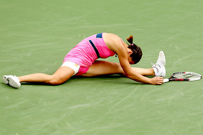 Jelena Jankovic does the split on the court after chasing after a shot against Simona Halep