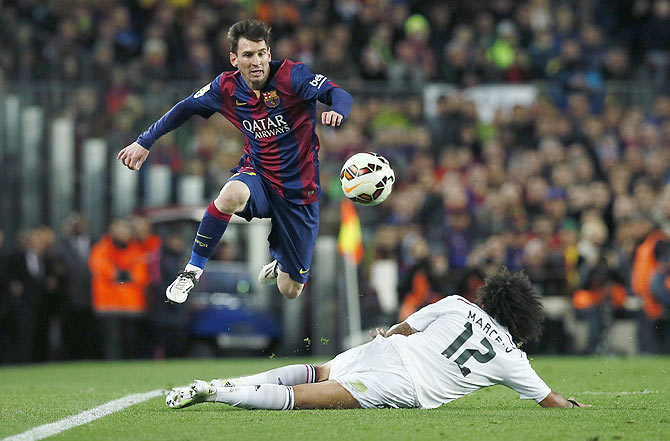 Barcelona's Lionel Messi (left) jumps as he as he intercepts a challenge by Real Madrid's Marcelo
