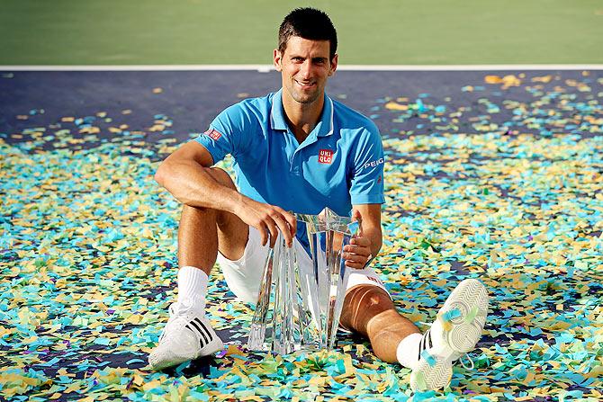 Novak Djokovic of Serbia poses for photographers after defeating Roger Federer of Switzerland to win the Indian Wells final on Sunday