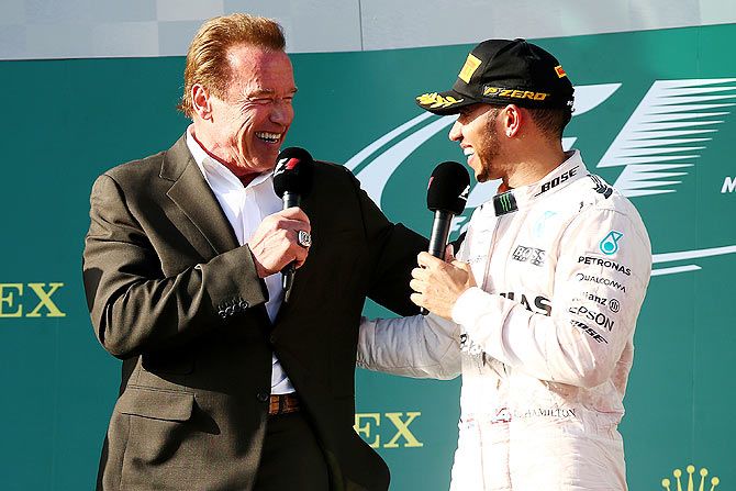 Lewis Hamilton of Great Britain and Mercedes GP speaks with actor Arnold Schwarzenegger as he celebrates on the podium after winning the Australian Formula One Grand Prix at Albert Park on March 15