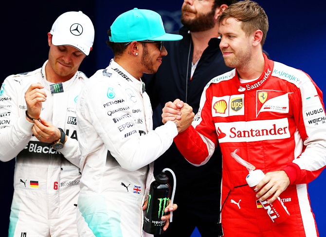 Lewis Hamilton of Great Britain and Mercedes GP celebrates next to Sebastian Vettel of   Germany and Ferrari and Nico Rosberg