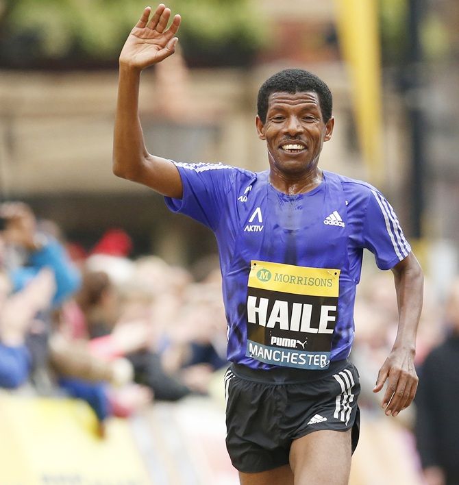 Ethiopia's Haile Gebrselassie waves as he approaches the finish line