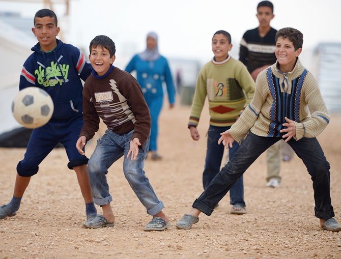Boys play football as Syrian refugees go about their daily business