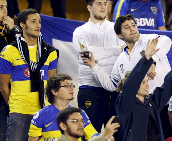 Boca Juniors' fan prepares to throw a bottle into the pitch 