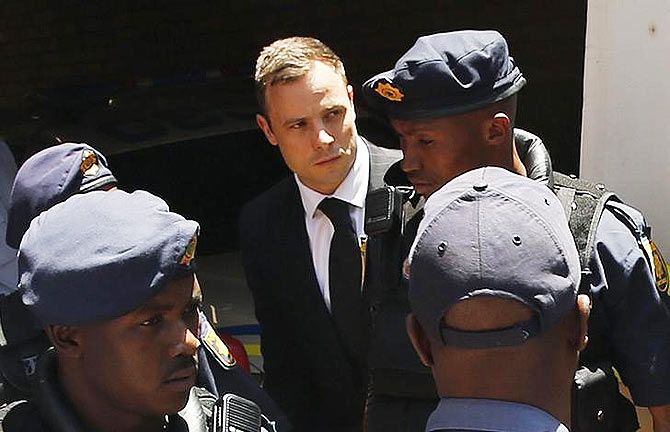 South African Olympic and Paralympic sprinter Oscar Pistorius (centre) is escorted to a police van after his sentencing at the North Gauteng High Court in Pretoria October 21, 2014