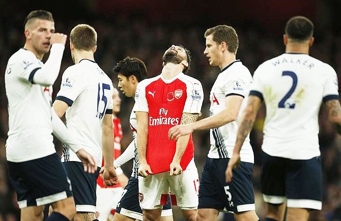 Arsenal's Olivier Giroud looks dejected after missing a chance to score a Tottenham players look on 