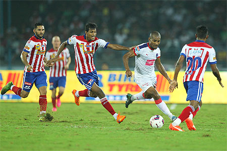 Delhi Dynamos' Florent Malouda runs with the ball past Atletico de Kolkata players