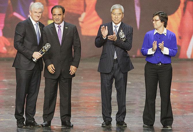 Australia national team representative, left, and Japan womens national team representative, second right, with the National Team of the Year trophies