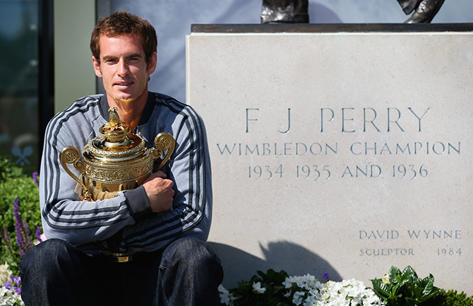 Andy Murray of Great Britain poses with the Gentlemen's Singles Trophy next to the Fred Perry statue at Wimbledon 