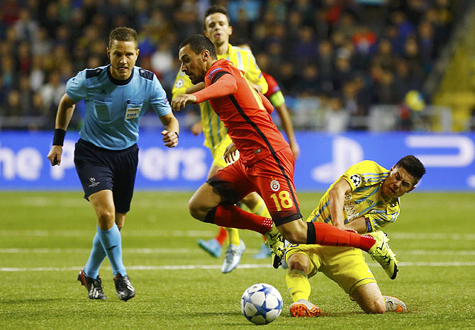 Astana's Georgi Zhukov (right) challenges Galatasaray's Sinan Gumus (centre) as referee Martin Strombergsson watches during their Champions League group C match at the Astana Arena stadium in Astana, Kazakhstan, on Wednesday