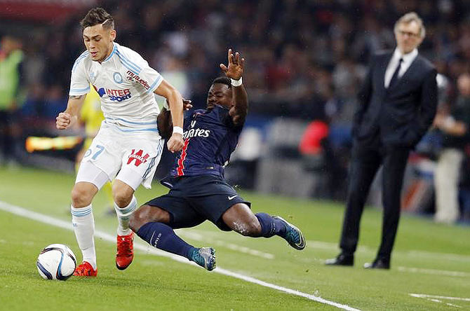 Paris St Germain's Serge Aurier (centre) challenges Olympique Marseille's Lucas Ocampos (left) as Paris St Germain head coach Laurent Blanc (right) looks on from the sidelines