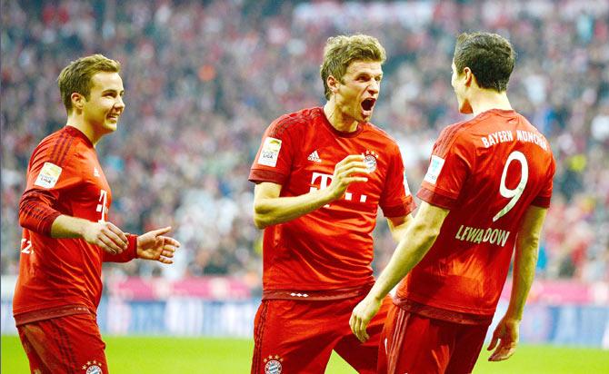 Bayern Munich's Robert Lewandowski (right) celebrates with teammates Thomas Mueller (centre) and Mario Goetze after scoring his team's third goal during their Bundesliga match against Borussia Dortmund at Allianz Arena in Munich on Sunday