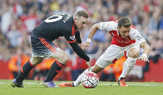 Manchester United's Wayne Rooney (left) and Arsenal's Mesut Ozil vie for possession