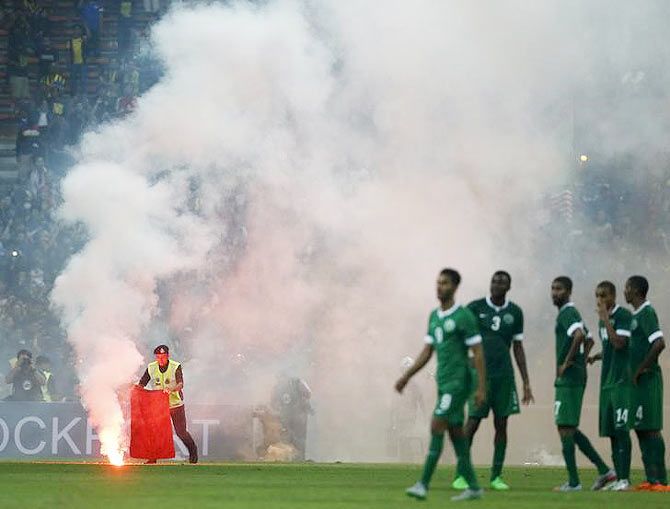 A police officer extinguishes a flare on the pitch during the 2018 World Cup qualifying soccer match between Malaysia and Saudi Arabia in Kuala Lumpur