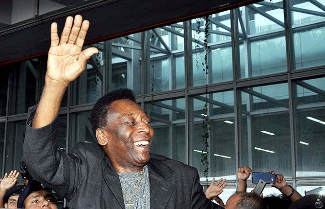 Brazilian football legend Pele waves to fans after his arrival at the Netaji Airport in Kolkata on October 11