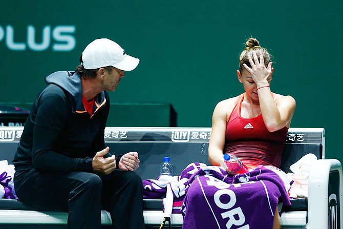 Simona Halep speaks with her coach Darren Cahil during a break in her round robin match against Agnieszka Radwanska