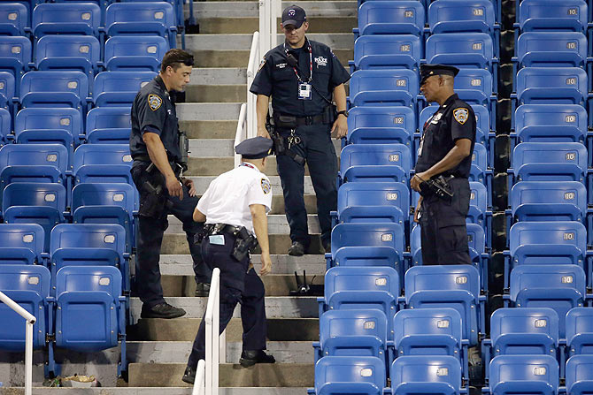 Police stand guard next to a drone after it crashed into the stands in Louis Armstrong Stadium during the during their Women's Singles second round match between Italy's Flavia Pennetta and Romania's Monica Niculescu at the USTA Billie Jean King National Tennis Center on Thursday