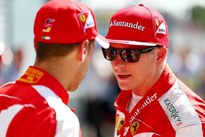 Ferrari's Kimi Raikkonen of Finland speaks to teammate and German driver Sebastian Vettel in Parc Ferme