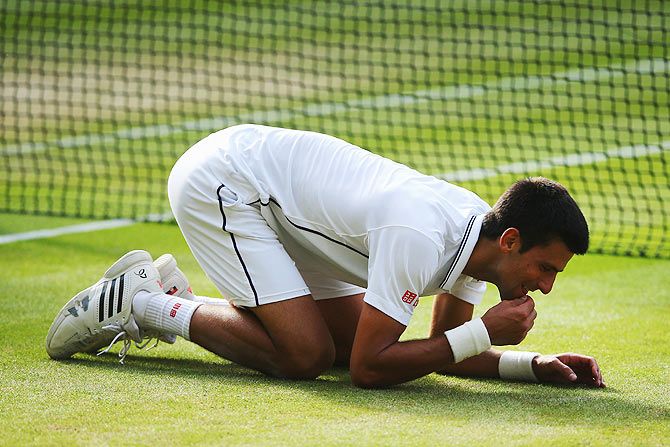 Novak Djokovic of Serbia eats some of the centre court grass as he celebrates winning the Wimbledon Championships against Roger Federer at the All England Lawn Tennis and Croquet Club on July 6, 2014