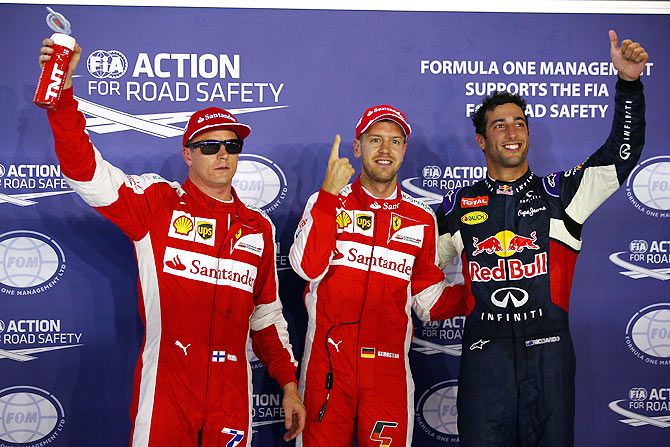 Ferrari'S Sebastian Vettel celebrates after claiming pole position with teammate Kimi Raikkonen (left) and Infiniti Red Bull Racing's Daniel Ricciardo (right) during qualifying for the Singapore Formula One Grand Prix