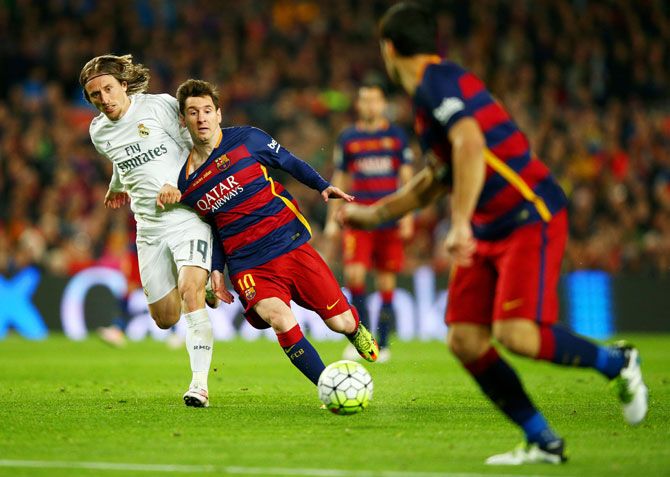 FC Barcelona's Lionel Messi is challenged by Real Madrid's Luka Modric 