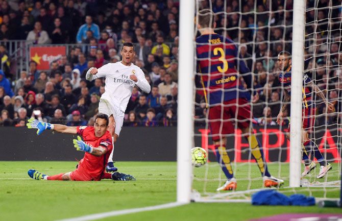 Real Madrid's Cristiano Ronaldo slides the ball underneat6h FC Barcelona's goalkeeper Claudio Bravo to score his team's winner during their La Liga El Clasico encounter at Camp Nou in Barcelona on Saturday