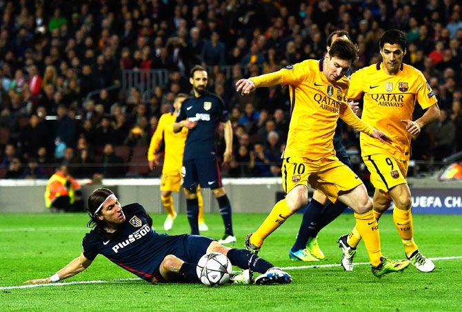 Barcelona's Lionel Messi is tackled by Atletico Madrid's Felipe Luis as Luis Suarez watches