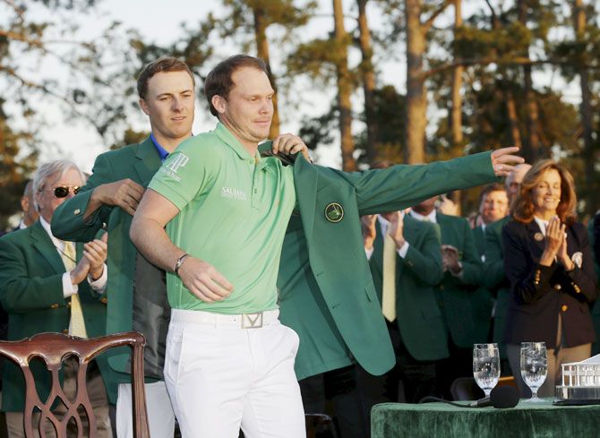 Danny Willett is helped into the green jacket by Jordan Spieth after winning the 2016 The Masters golf tournament at Augusta National Golf Club
