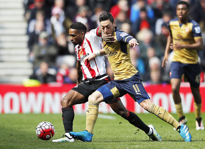 Arsenal's Mesut Ozil is challenged by Sunderland's Jermain Defoe during their English Premier League match at the Stadium of Light on Sunday