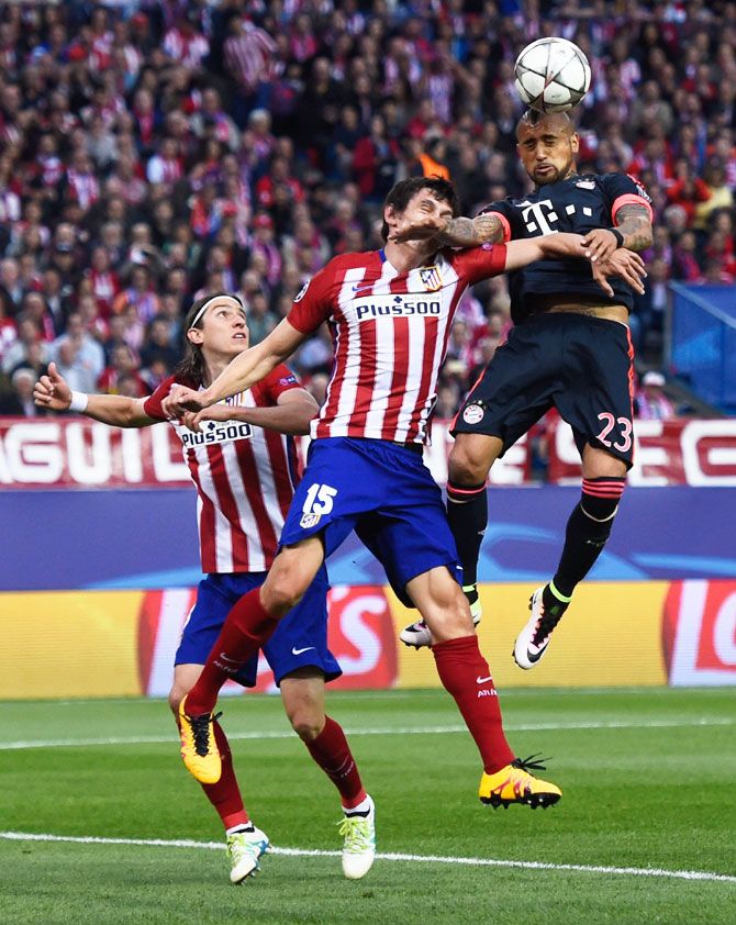 Bayern Munich's Arturo Vidal outjumps Atletico Madrid's Felipe Luis and Stefan Savic (15) to win a header