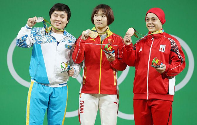 Gold medalist, Yanmei Xiang of China (centre), silver medalist Zhazira Zhapparkul of Kazakhstan and bronze medalist Sara Ahmed of Egypt pose on the podium after the Women's 69kg Group A weightlifting contest on Wednesday