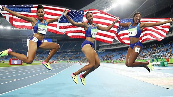 From left, bronze medalist Kristi Castlin, gold medalist Brianna Rollins and silver medalist Nia Ali of the United States celebrate with American flags after the women's 100m hurdles final on August 17