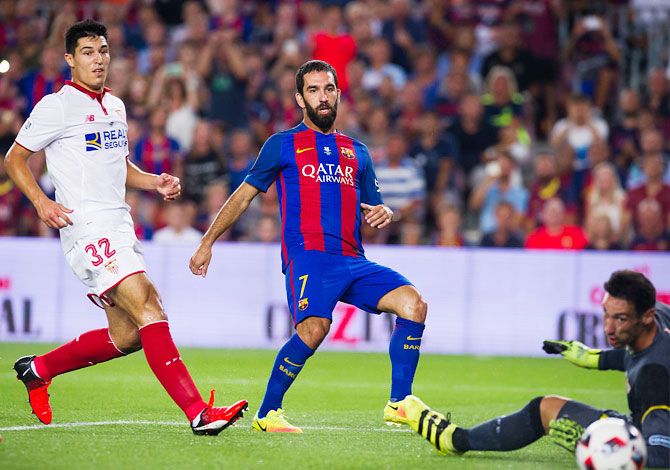 FC Barcelona's Arda Turan (centre) shoots the ball past Sevilla goalkeeper Sergio Rico and Diego Gonzalez (left) to score the opening goal during the Spanish Super Cup Final second leg match on Wednesday
