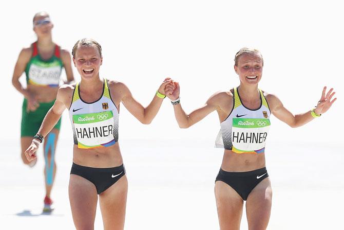 Anna Hahner (left) of Germany and her sister Lisa Hahner react as they approaches the finish line during the Women's Marathon of the Rio 2016 Olympic Games at the Sambodromo on August 14