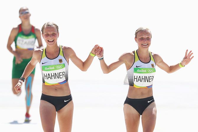Anna Hahner (left) of Germany and her sister Lisa Hahner react as they approaches the finish line during the Women's Marathon of the Rio 2016 Olympic Games at the Sambodromo on August 14