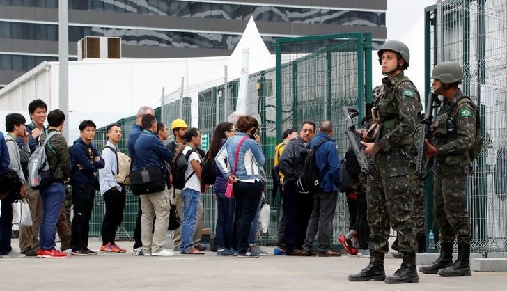 People queue at a security check to enter the main press center as Brazilian military police soldiers provide security at the 2016 Rio Olympics Park in Rio de Janeiro