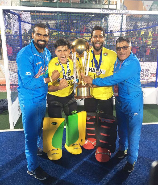India's senior hockey team captain and goal-keeper P Sreejesh (left), India's junior hockey team 'keepers and coach pose with the Junior Hockey World Cup Trophy