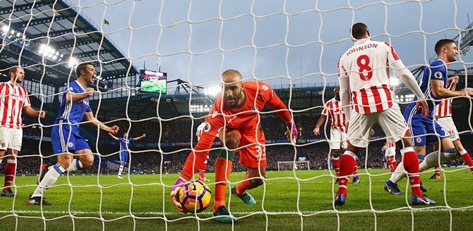 Goalkeeper Lee Grant of Stoke City grabs the ball as Gary Cahill, right, of Chelsea celebrates as he scores the opening goal during the Premier League match