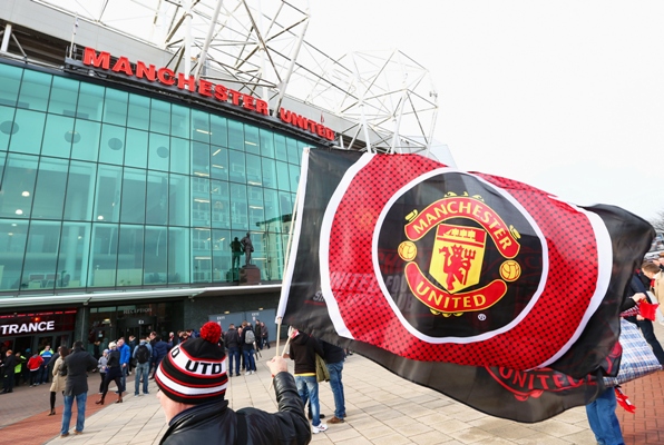 A Manchester United supporter waves the flag prior to a Premier League match at Old Trafford 