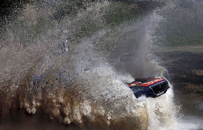 Sebastien Loeb of France drives his Peugeot through the water during the Buenos Aires-Rosario prologue stage of Dakar Rally 2016 in Arrecifes, Argentina, on January 2, 2016