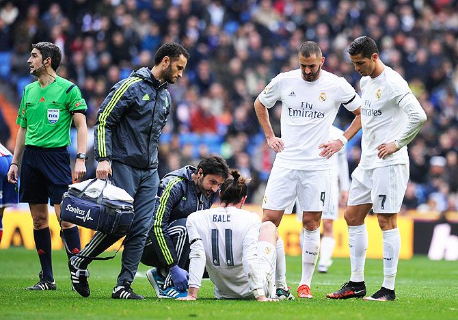 Real Madrid's Gareth Bale lies injured as Cristiano Ronaldo and Karim Benzema watch him get treated by medical staff during their La Liga match against Sporting Gijon at Estadio Santiago Bernabeu on Sunday