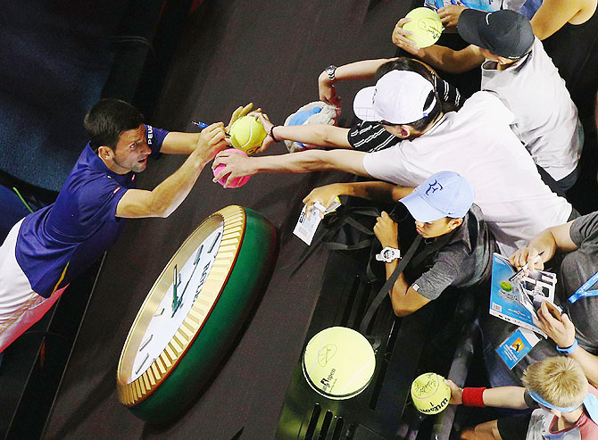 Novak Djokovic signs autographs after winning his quarter-final match against Kei Nishikori
