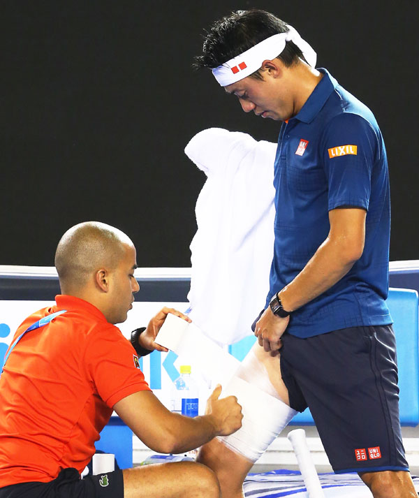 Kei Nishikori has his thigh strapped by a medical staff during his quarter-final against Novak Djokovic