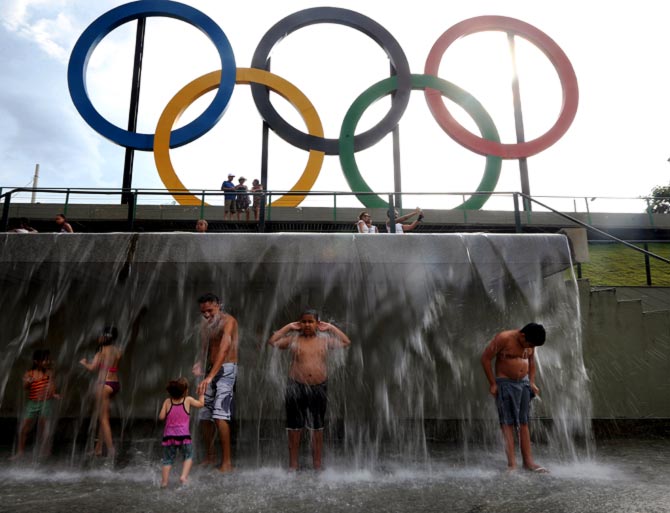  People cool off beneath a water fountain beneath the Olympic rings in Madureira Park in Rio de Janeiro