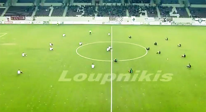 A video grab shows players of AEL Larissa and Acharnaikos sit on the pitch in protest before kick-off of their Greek 2nd division match in  in the Thessalian city of Larissa on Friday