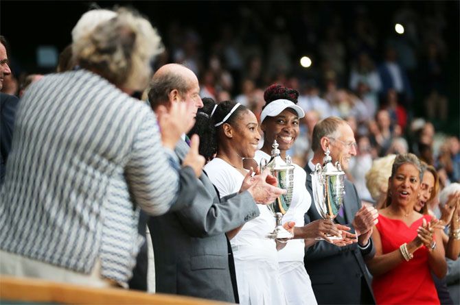 Serena and Venus Williams pose with their Wimbledon doubles trophy on Saturday