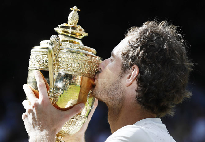 Britain's Andy Murray kisses the trophy as he celebrates winning his Wimbledon win against Canada's Milos Raonic on Saturday